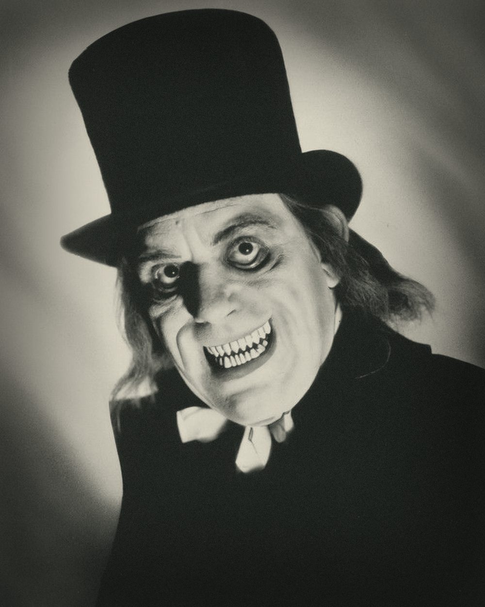 Lon Chaney as the Man in the Beaver Hat: top hat, ringed eyes and a wide grin of sharpened teeth. Publicity portrait, 1927